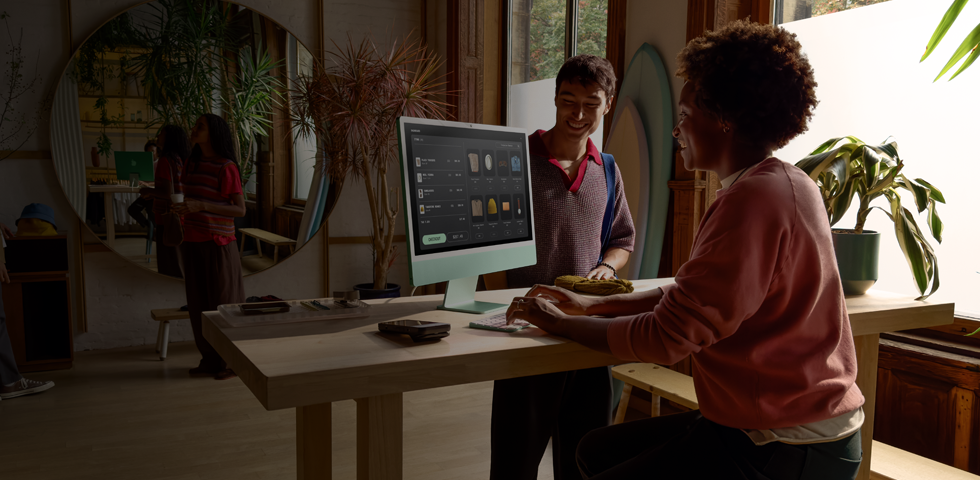 Ein Verkäufer bearbeitet eine Transaktion für seinen Kunden problemlos auf einem 24 Zoll iMac in Grün